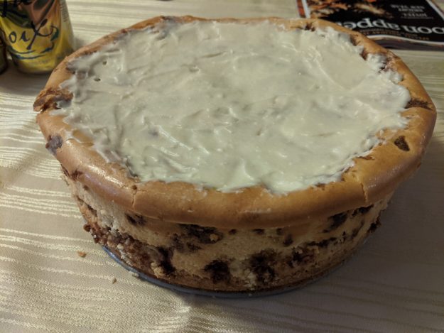 large cheesecake with frosting and cinnamon swirls on table