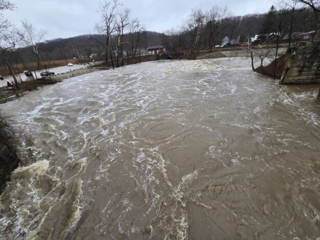 Very full Cuyahoga River, brown with dirt, swirling, high on banks