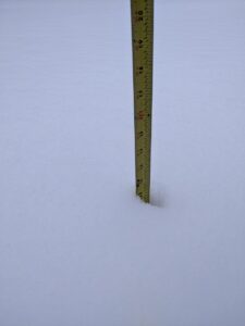 a tape measure shows snow depth aproaching 12"