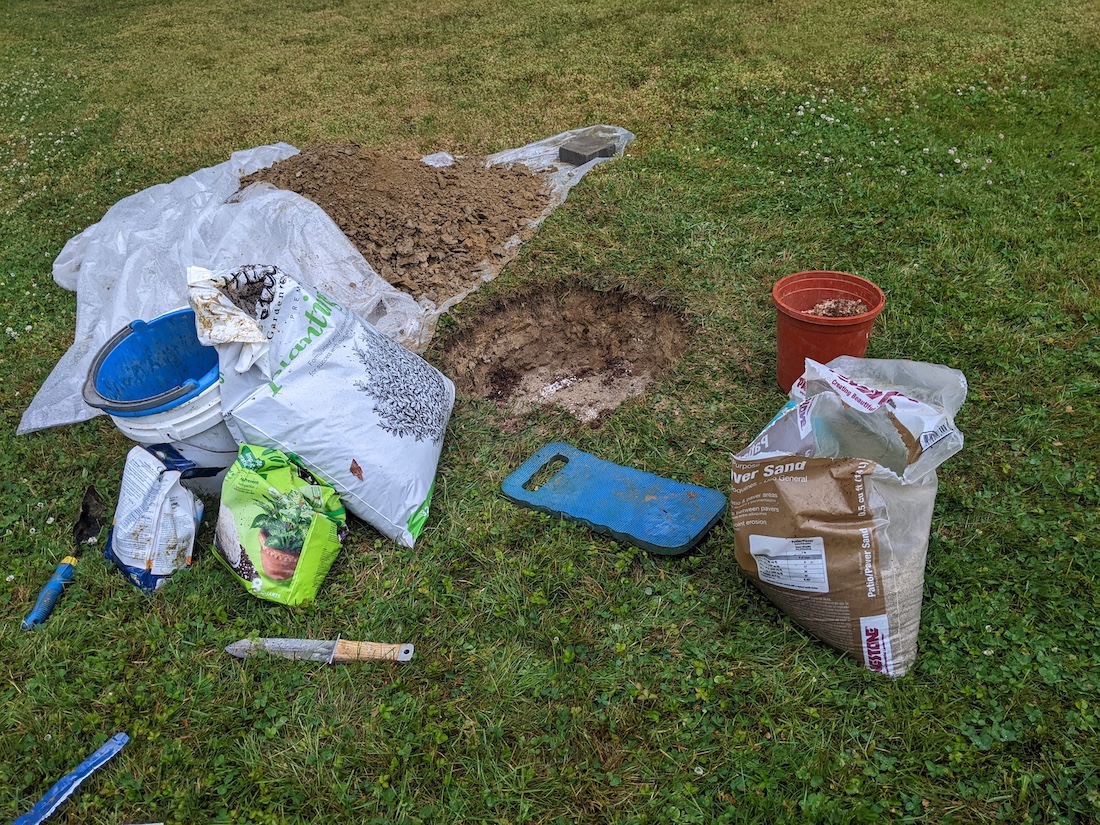 Tree hole dug to depth, with dirt pile and new fill nearby